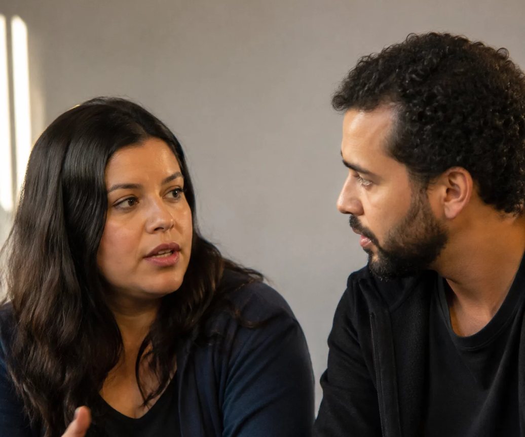 Participante de mão levantada à mesa, pedindo a vez de responder